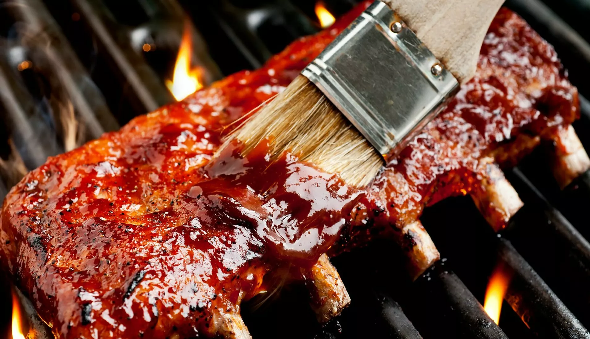 marinade blir penslet på kjøtt som ligger på grillen