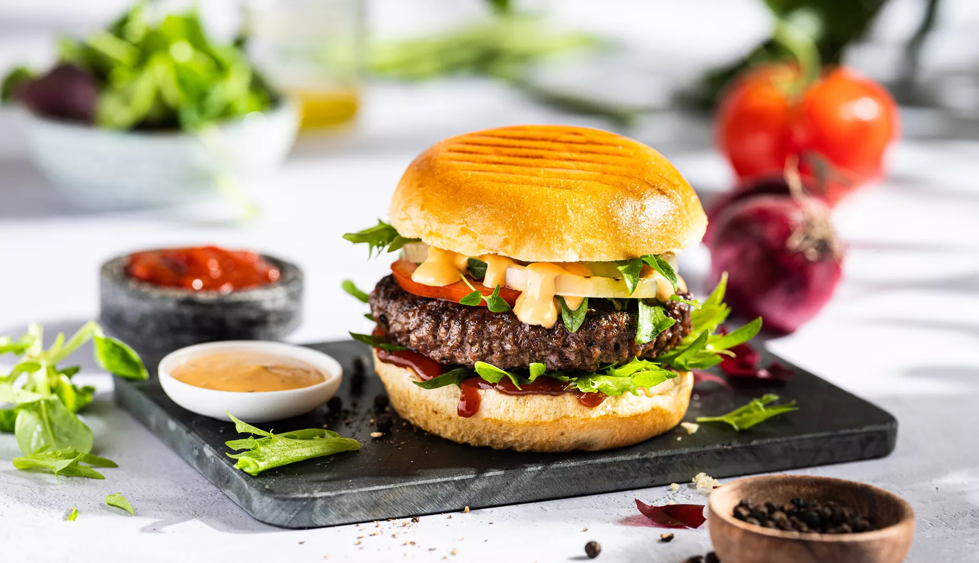 saftig hamburger på en fjøl med dipsauser ved siden av