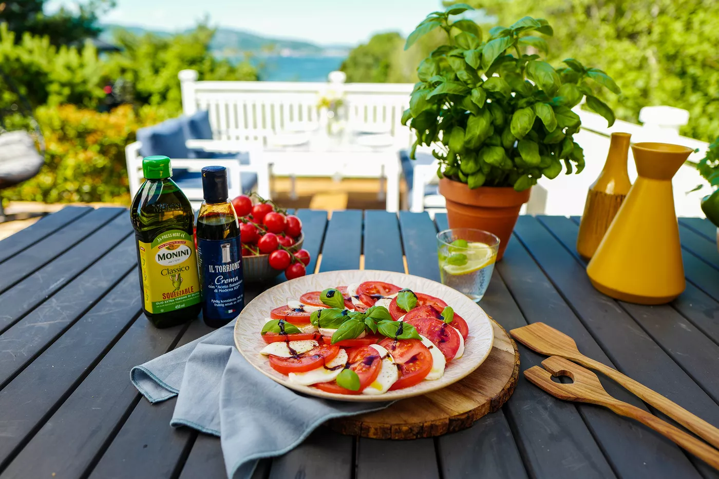 En tallerken caprese står på et terassebord med fin utsikt i bakgrunnen