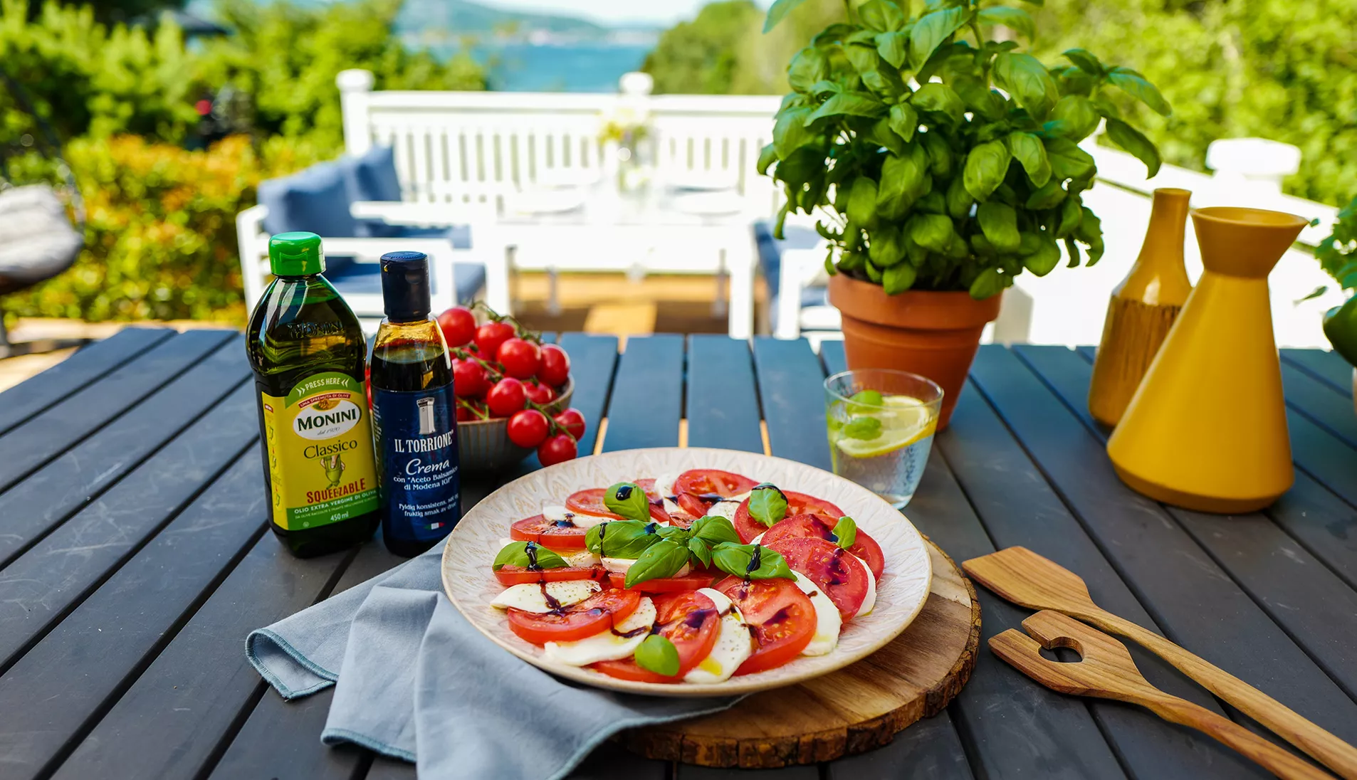En tallerken caprese står på et terassebord med fin utsikt i bakgrunnen
