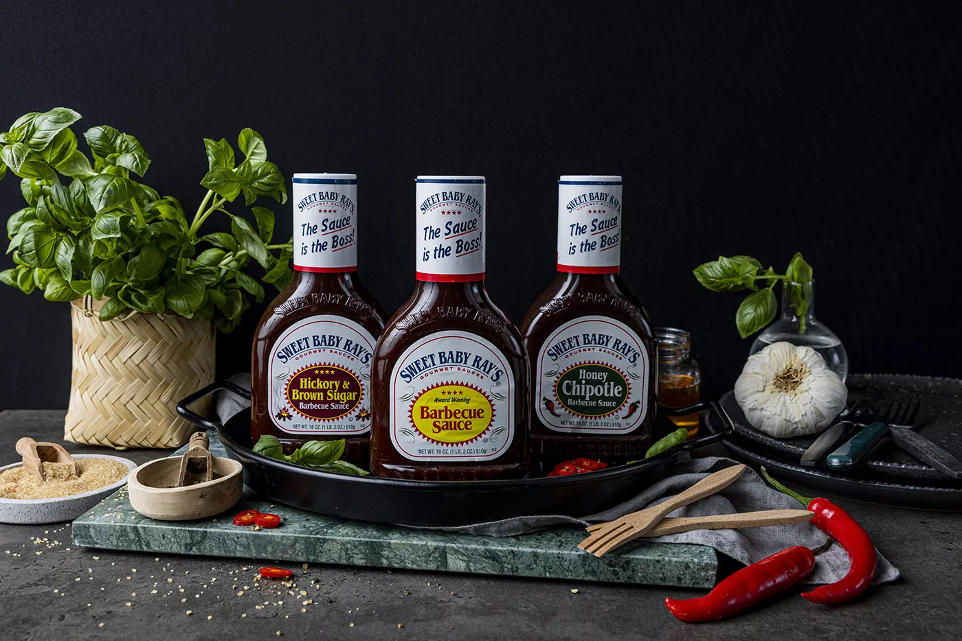 Tre flasker med Sweet Baby Ray's BBQ-saus på et bord